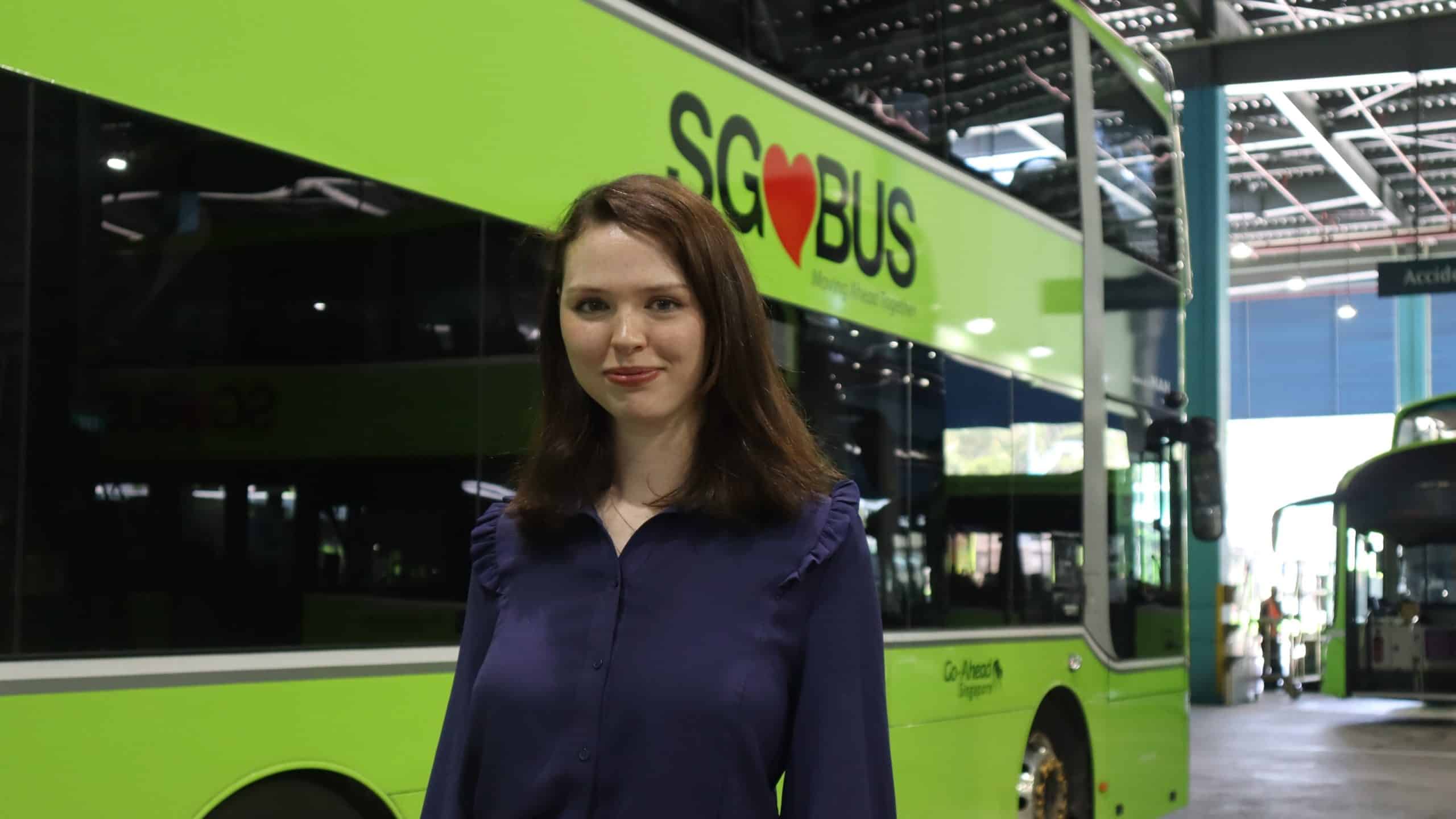 a woman standing in front of a green bus