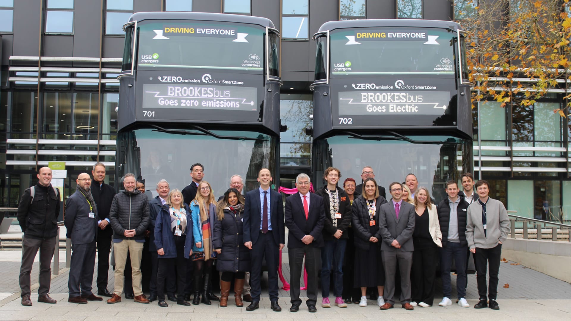 a group of people standing in front of a double decker bus