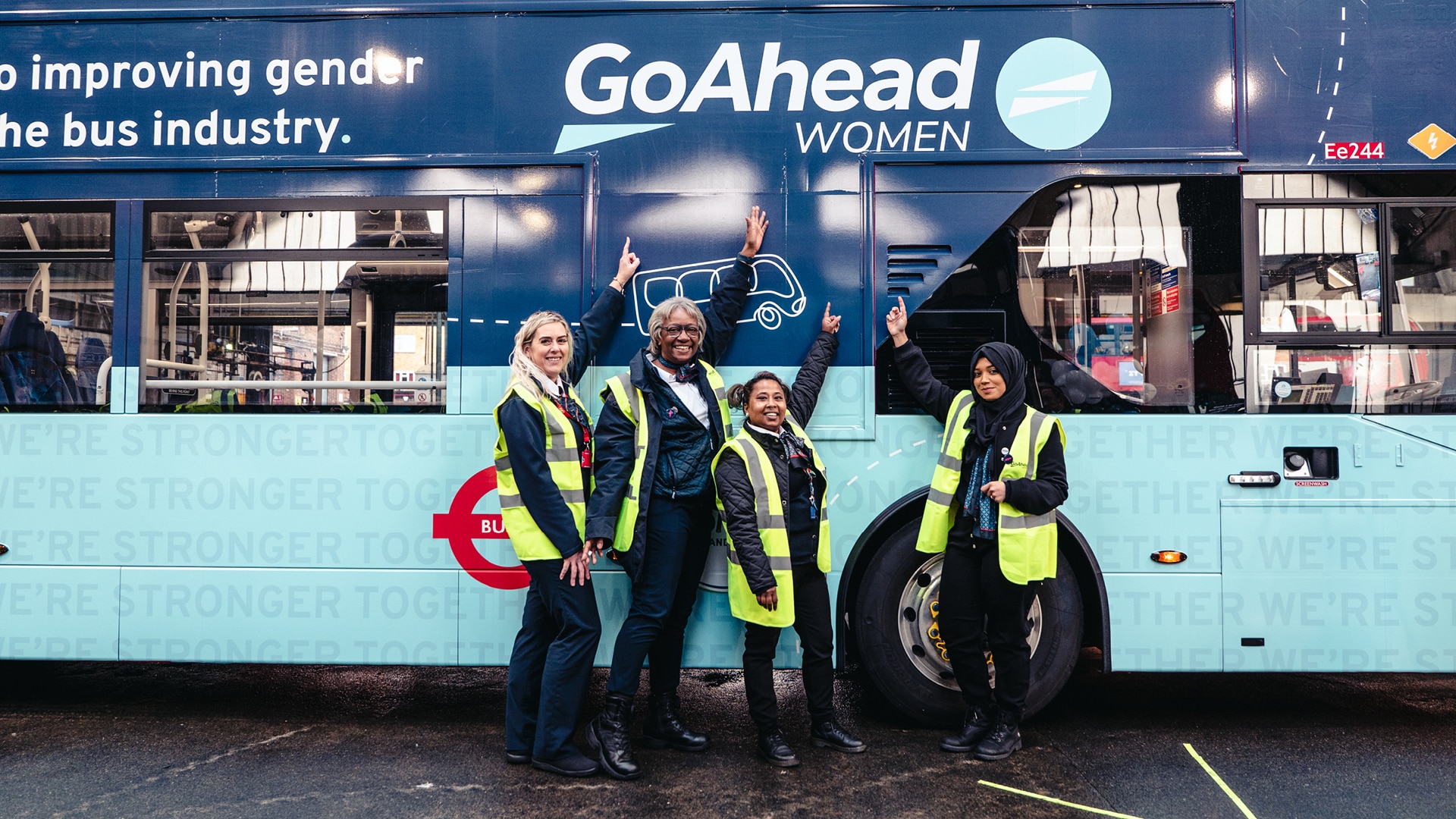 a group of women in reflective vests posing in front of a bus